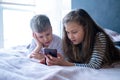 Two kids caucasian boy and girl playing games or looking information video text at Internet on mobile phones at home Royalty Free Stock Photo