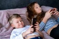 Two kids caucasian boy and girl playing games or looking information video text at Internet on mobile phones at home Royalty Free Stock Photo