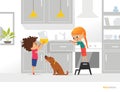 Two kids cooking their own breakfast. Boy holding pitcher with orange juice, girl opening kitchen box and funny dog. Independent c Royalty Free Stock Photo