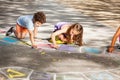 Two kids draw outside in chalk hopscotch