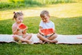 Two kids eat watermelon in the garden. Kids eat fruit outdoors. Healthy snack for children.Toddlers girl and boy enjoy