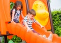 Two kids friends having fun to play together on children`s slide