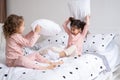 two kids girls in pajamas having pillow fight on bed in modern bright apartment Royalty Free Stock Photo