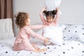 two kids girls in pajamas having pillow fight on bed in modern bright apartment Royalty Free Stock Photo