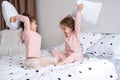 two kids girls in pajamas having pillow fight on bed in modern bright apartment Royalty Free Stock Photo