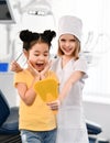 Two kids girls play dentist and happy patient in dental office.