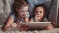 two kids girls under the blanket with a digital tablet. kid dream online video games at concept. daughters kids watching Royalty Free Stock Photo