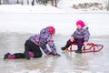 Two kids have fun sitting together on the ice and playing with a snow sled on a clear winter day Royalty Free Stock Photo