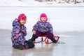 Two kids have fun sitting together on the ice and playing with a snow sled on clear winter day Royalty Free Stock Photo