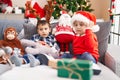 Two kids holding ball sitting on sofa by christmas tree at home Royalty Free Stock Photo