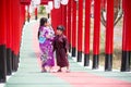 Two kids in kimono walking into at the shrine red gate, in Japanese garden Royalty Free Stock Photo