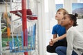 Two kids kneeling and looking at a science exhibit