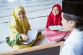 two kids learning to read quran and point to black board with muslim teacher or ustad Royalty Free Stock Photo