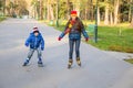 Two kids learning to ride in autumn park on rollerblades Royalty Free Stock Photo