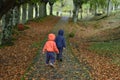 Two kids in orange and blue coats walking through a path in the park in autumn Royalty Free Stock Photo