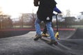 two kids play with their stunt scooters upon elevation in modern asphalted pump track fun park.