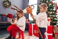 Two kids playing with reindeer rocking and horse toy standing by christmas tree at home Royalty Free Stock Photo