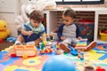 Two kids playing xylophone and tambourine sitting on floor at kindergarten