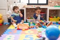 Two kids playing xylophone and tambourine sitting on floor at kindergarten