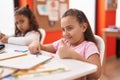 Two kids preschool students drawing on paper doing ok gesture at classroom