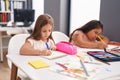 Two kids preschool students sitting on table drawing on paper at classroom