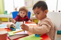 Two kids preschool students sitting on table drawing on paper at kindergarten