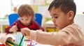 Two kids preschool students sitting on table drawing on paper at kindergarten