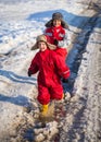 Two kids in rainboots running on the ice puddle Royalty Free Stock Photo