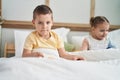 Two kids reading story book sitting on bed at bedroom Royalty Free Stock Photo