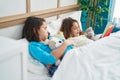 Two kids reading story book sitting on bed at bedroom Royalty Free Stock Photo