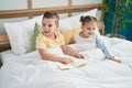 Two kids reading story book sitting on bed at bedroom Royalty Free Stock Photo