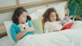 Two kids reading story book sitting on bed at bedroom Royalty Free Stock Photo