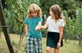 Two kids relaxing outdoors at summer park. Brother and sister happy walking in nature. Siblings boy and girl playing in