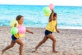 Two kids running on beach with color balloons. Royalty Free Stock Photo