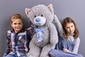 Two Kids Sitting With Big Teddy Bear.