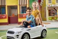Two kids sitting in toy car and looking at camera. Royalty Free Stock Photo