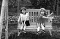 Two kids swinging and relaxing outdoors at summer park. Brother and sister happy walking in nature. Siblings boy and