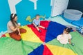 two kids and a teacher sitting on the floor and playing with balls at the nursery, concentration game concept Royalty Free Stock Photo