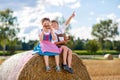 Two kids in traditional Bavarian costumes in wheat field. German children eating bread and pretzel during Oktoberfest