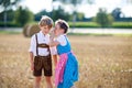 Two kids, boy and girl in traditional Bavarian costumes in wheat field with hay bales Royalty Free Stock Photo