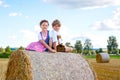 Two kids, boy and girl in traditional Bavarian costumes in wheat field with hay bales Royalty Free Stock Photo