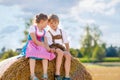 Two kids in traditional Bavarian costumes in wheat field. German children sitting on hay bale during Oktoberfest. Boy Royalty Free Stock Photo