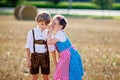 Two kids, boy and girl in traditional Bavarian costumes in wheat field with hay bales Royalty Free Stock Photo