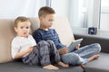 Two kids using gadgets at home. Brothers with tablet computer in light room. Boys playing games on tablet pc, emotions. Royalty Free Stock Photo