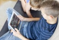 Two kids using tablet at home. Brothers with tablet computer in light room. Boys playing games on tablet pc, emotions. Royalty Free Stock Photo