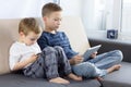 Two kids using tablet pc and smartphon at home. Brothers with tablet computer in light room. Boys playing games on tablet computer Royalty Free Stock Photo