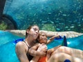 Two kids on a water ride through with a large aquarium