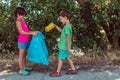 Two kind children doing school tasks and collecting garbage with a plastic bag in the park Royalty Free Stock Photo