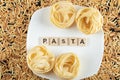 Two kinds of pasta on white plate and scattered on surface