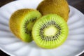 Two kiwi fruits on white plate  one kiwi cut in half. Close-up Royalty Free Stock Photo